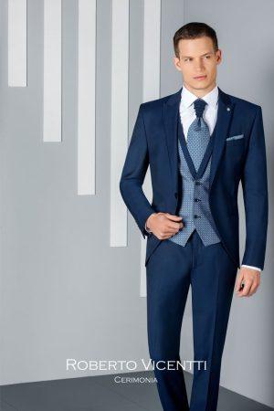 Traje de novio azul marino con chaleco y corbatón azul claro de patrón geométrico