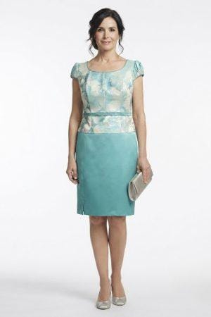 Modelo posando con un conjunto midi de tres piezas en tono turquesa, cuerpo estampado y falda satinada.
