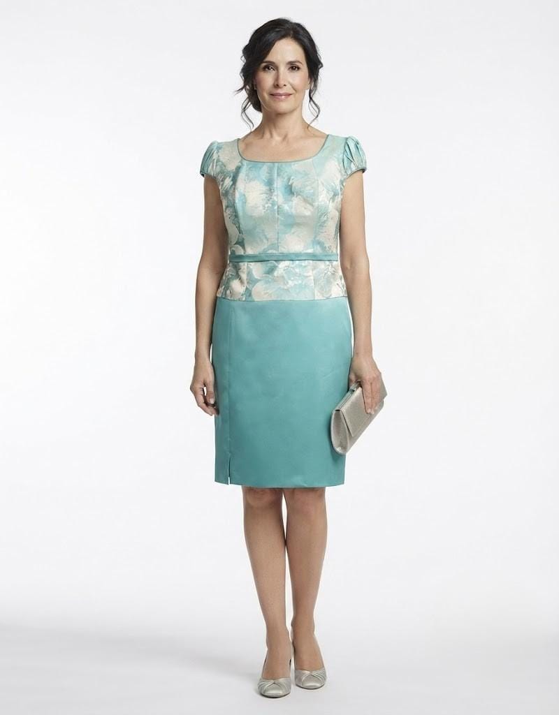 Modelo posando con un conjunto midi de tres piezas en tono turquesa, cuerpo estampado y falda satinada.