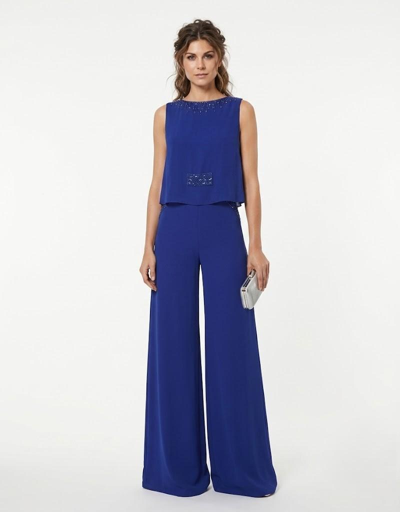 Mujer luciendo un elegante mono largo de fiesta azul eléctrico con pernera ancha y pedrería de frente.