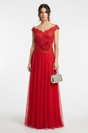 Mujer luciendo un elegante vestido largo de fiesta rojo con escote Bardot y detalle de flor en la cintura de frente.