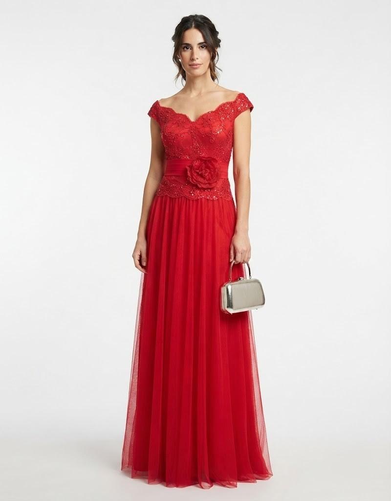 Mujer luciendo un elegante vestido largo de fiesta rojo con escote Bardot y detalle de flor en la cintura de frente.