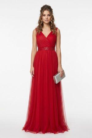 Mujer luciendo un elegante vestido largo de fiesta rojo de tul con cuerpo drapeado y cinturón brillante de frente.