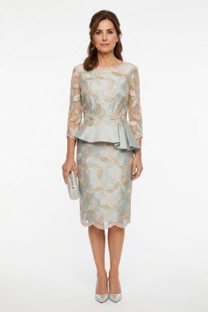 Vista frontal de conjunto midi con peplum y bordado floral en tonos suaves.