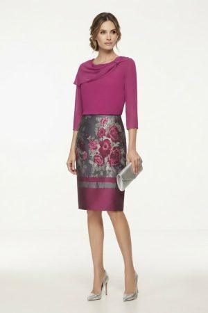 Modelo luciendo un elegante conjunto de ceremonia con cuerpo fucsia y falda estampada floral.