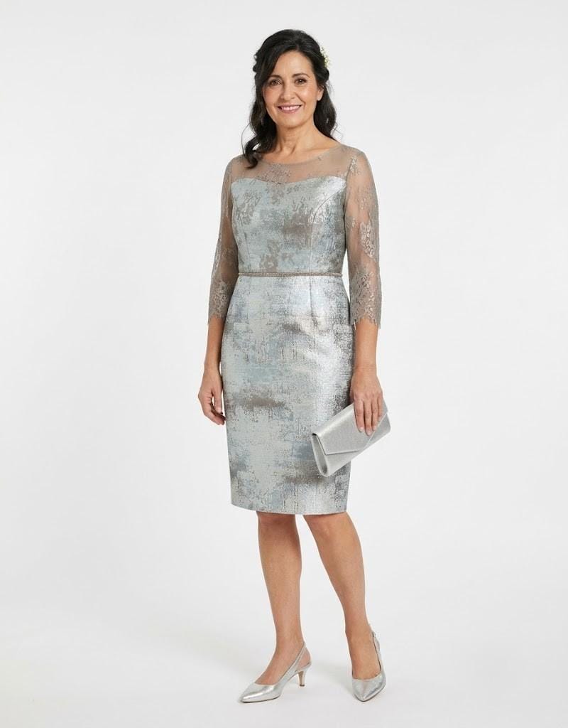 Modelo luciendo un conjunto de vestido y chaqueta elegante en tono plateado para madrinas.