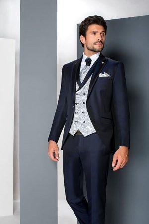 Traje de novio azul marino con chaleco cruzado plateado y corbata de cachemir