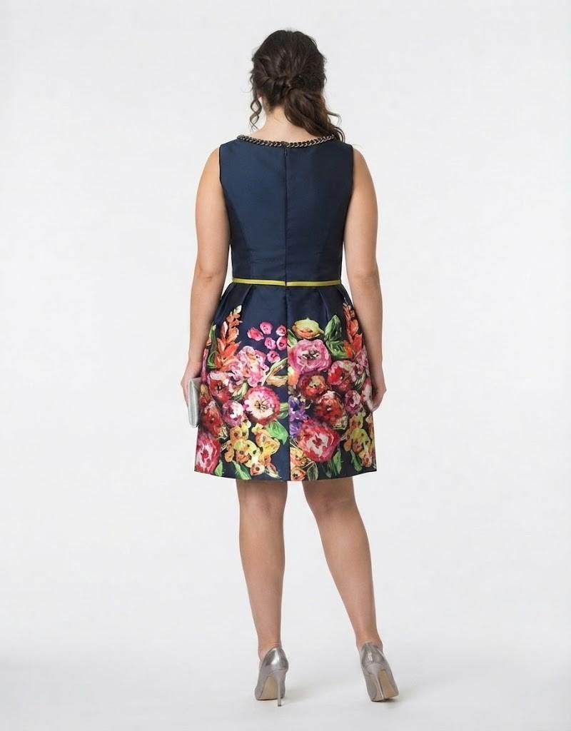 Vista trasera de modelo curvy con vestido corto de fiesta azul marino y detalles florales.