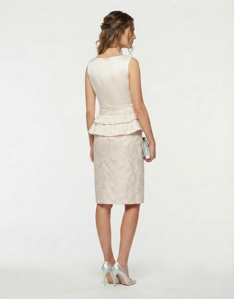 Vista trasera de modelo con vestido corto marfil de ceremonia y diseño peplum.