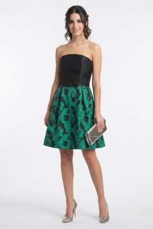Modelo luciendo un elegante vestido corto negro y verde de ceremonia con escote palabra de honor.