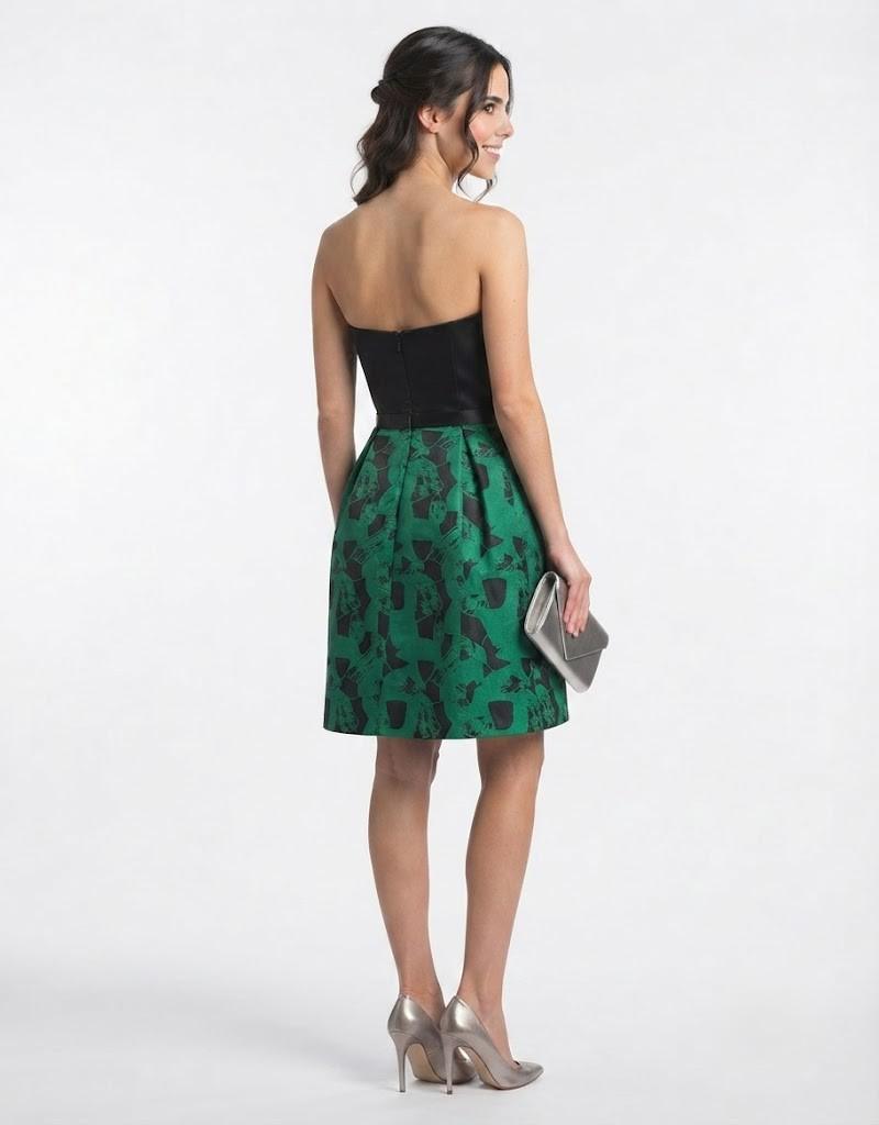 Vista trasera de modelo con vestido corto negro y verde de ceremonia y escote palabra de honor.