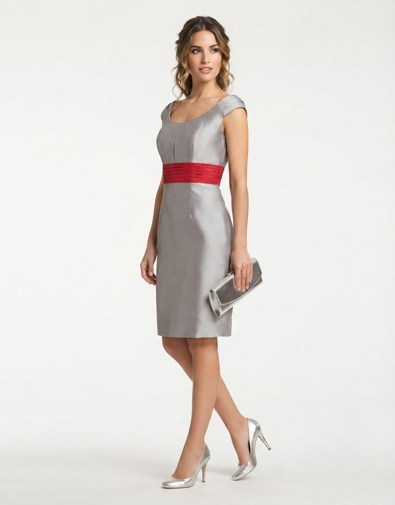 Modelo luciendo un elegante vestido gris de ceremonia con fajín rojo y bolso plateado.