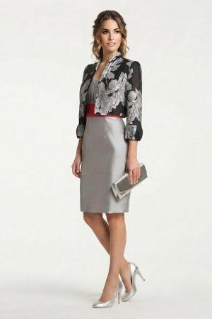 Modelo con vestido gris de ceremonia, fajín rojo y chaqueta corta estampada floral.