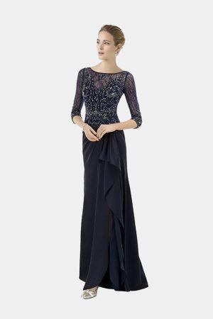 Vista frontal de modelo luciendo un vestido largo azul marino de fiesta con manga francesa y abertura lateral con volantes.