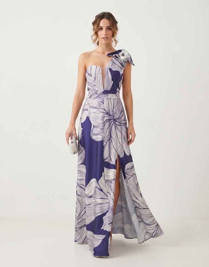 Vista frontal de modelo luciendo un vestido largo estampado de fiesta con un solo hombro, lazo decorativo y abertura en la pierna.