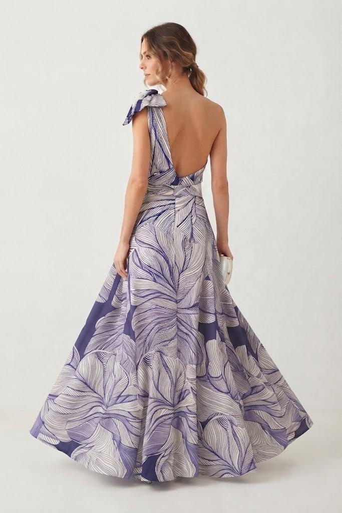 Vista trasera de mujer con vestido largo estampado de fiesta destacando el diseño asimétrico de la espalda y la amplitud de la falda.