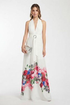 Mujer luciendo un vestido largo de fiesta blanco con estampado floral y cinturón de hebilla de frente.