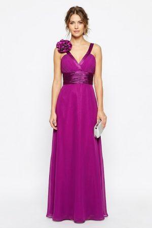 Mujer luciendo un elegante vestido largo de fiesta morado con escote en V y flor decorativa en el hombro