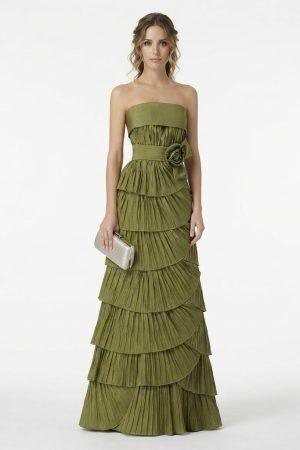 Mujer luciendo un elegante vestido largo de fiesta verde oliva con palabra de honor, volantes plisados y flor en la cintura