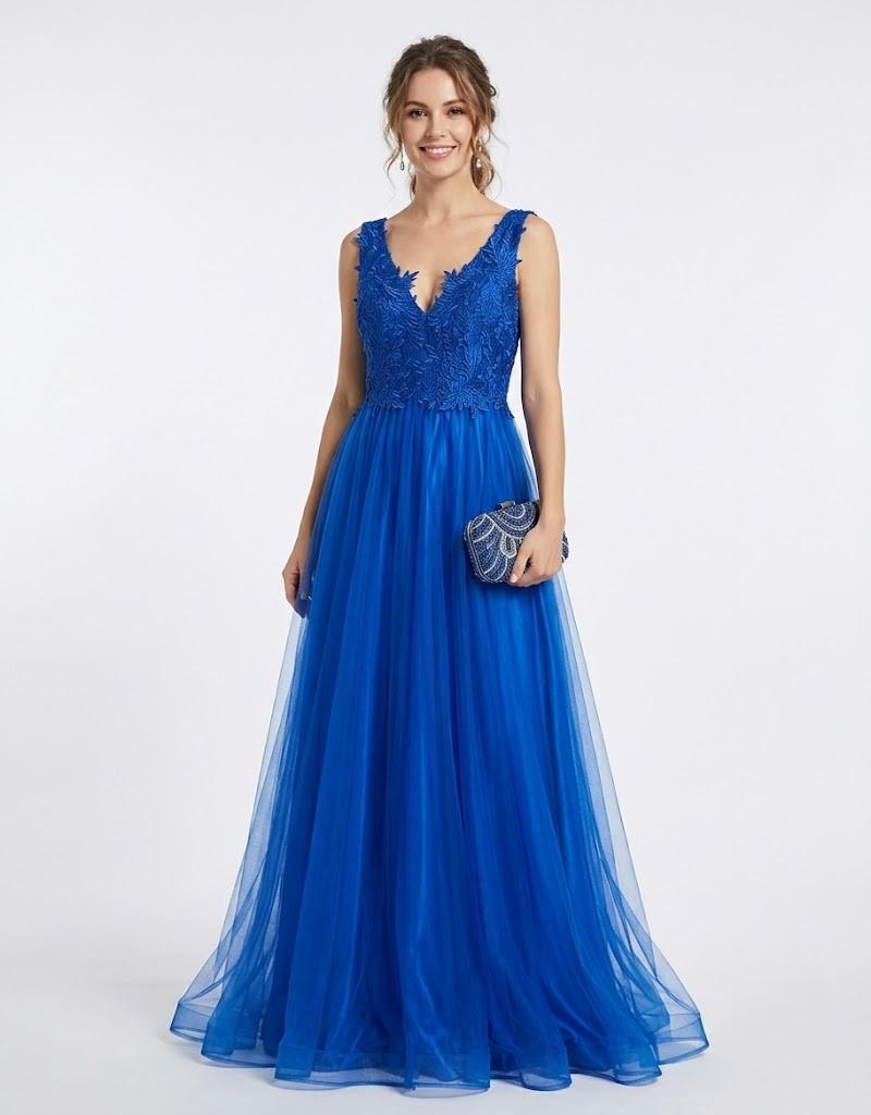 Modelo posando con un vestido largo de fiesta azul de tul con detalles de encaje bordado de frente.