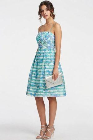 Mujer con vestido midi de estampado floral y rayas con escote recto y clutch plateado.