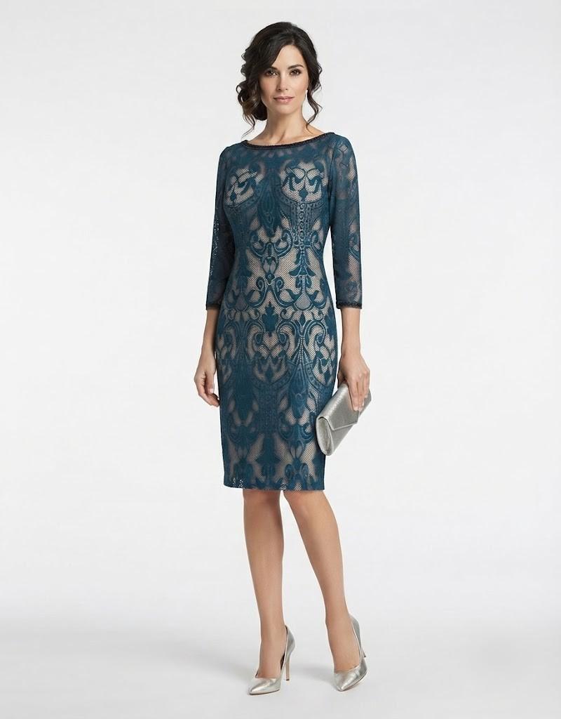 Modelo posando de frente con un vestido midi azul petróleo de encaje con diseño intrincado.