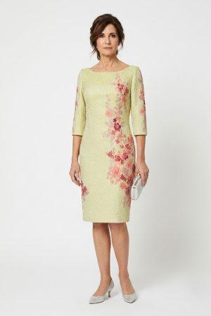 Modelo de frente luciendo un diseño midi en jacquard amarillo claro con aplicaciones de tul bordado floral.