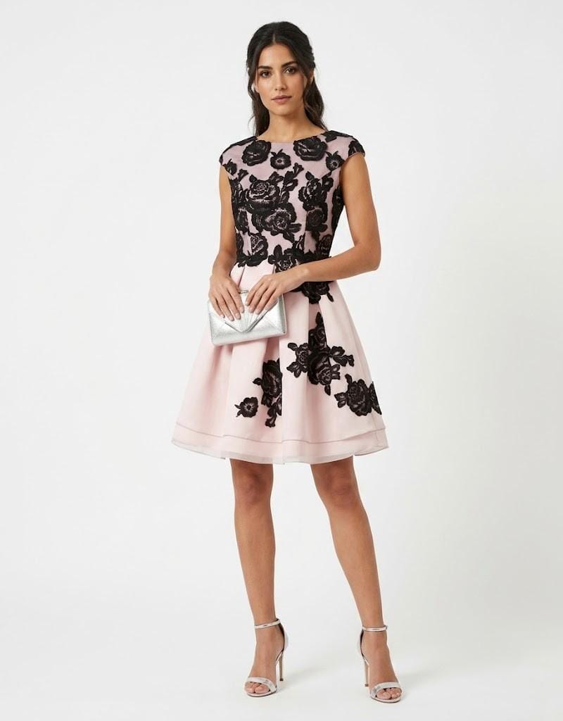 Mujer vistiendo vestido corto de fiesta color rosa con detalles de encaje floral negro.