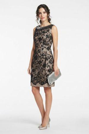 Modelo luciendo vestido de fiesta corto de encaje negro con detalle de pedrería en el cuello y bolso plateado.