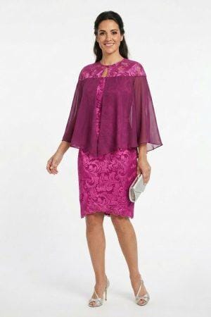 Mujer luciendo un vestido de fiesta corto color magenta con patrón de encaje floral y escote redondo y capa.