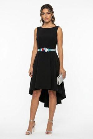 Modelo luciendo vestido de fiesta corto color negro con corte asimétrico y cinturón floral decorativo.