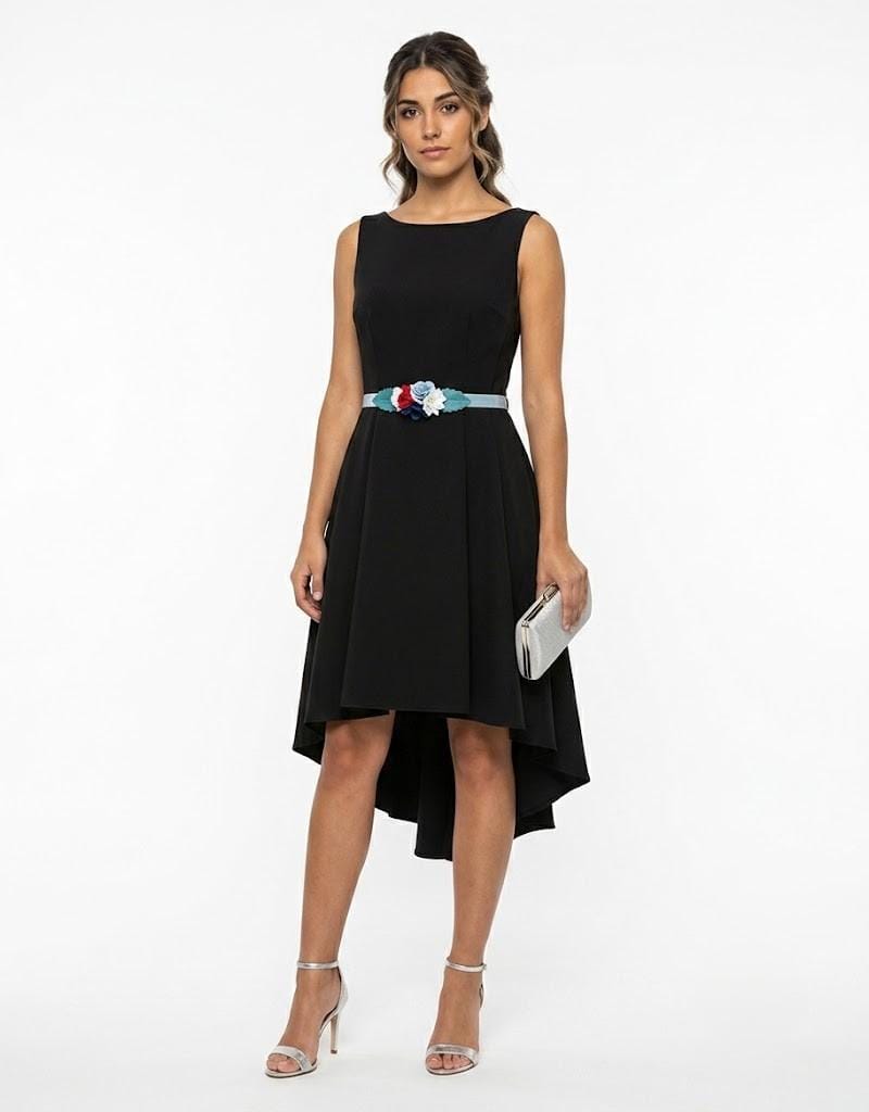 Modelo luciendo vestido de fiesta corto color negro con corte asimétrico y cinturón floral decorativo.